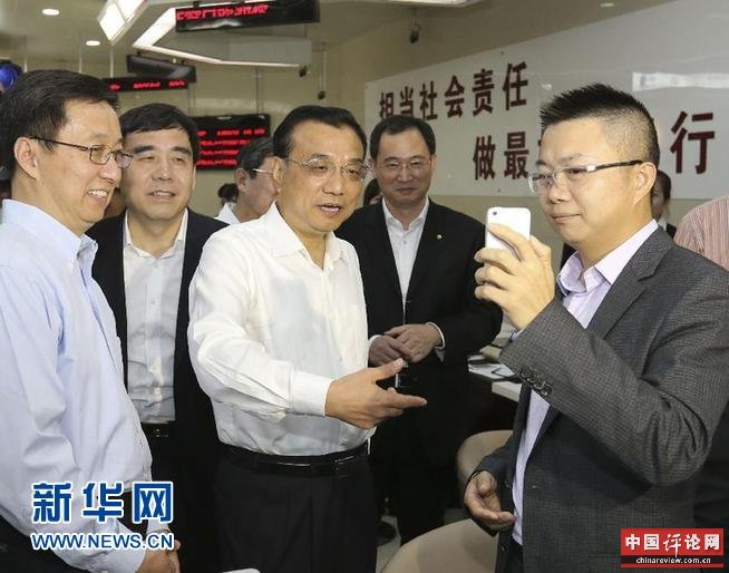 9月18日至19日，中共中央政治局常委、国务院总理李克强在中国（上海）自由贸易试验区考察。这是9月18日，在中国银行自贸区分行办理业务的吴先生通过手机视频，将正在这里考察的李克强总理“秀”给香港客户，总理愉快地和视频中的港商打招呼。新华社记者丁林 摄