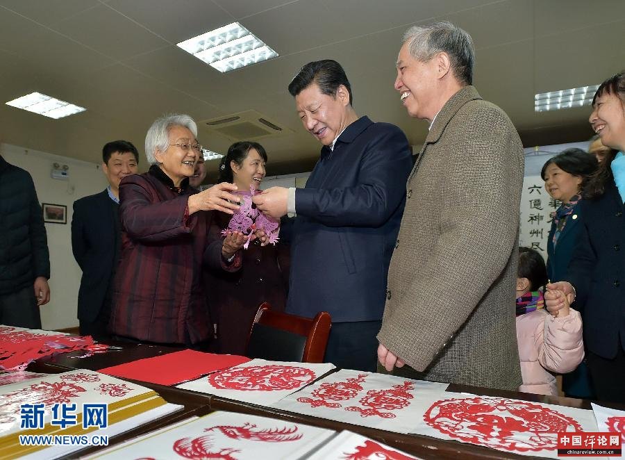 这是15日上午，习近平在西安市雁塔区电子城街道二〇五所社区服务中心欣赏社区老人的剪纸作品。新华社记者 李涛 摄 