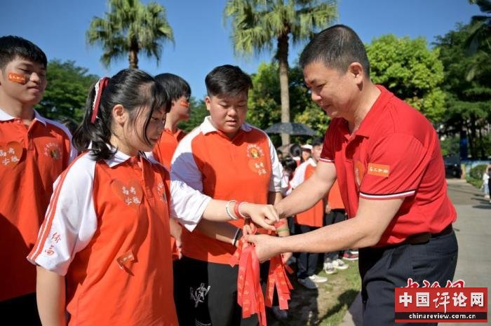 资料图：广西华侨实验高中的教师为高三学子系上红丝带，盼望学子高考必胜。 俞靖 摄